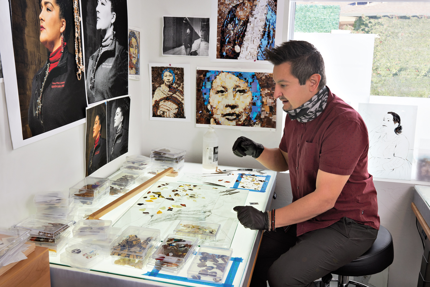 Artist Benjamin Timpson sitting at a table surrounded by images of women and butterfly wings