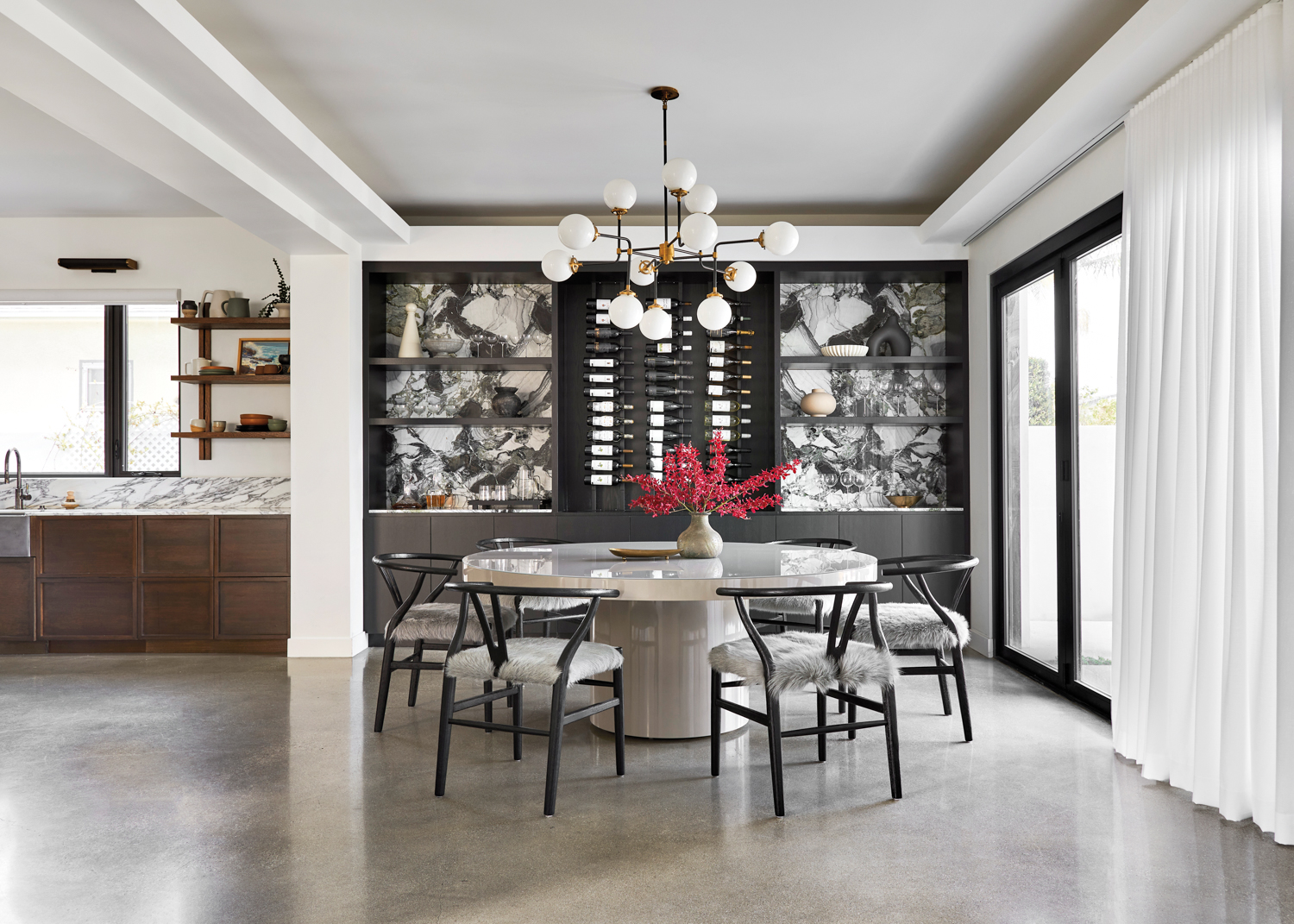 dining room with black wishbone chairs, circular pedestal table, wine cabinet and marble backsplash