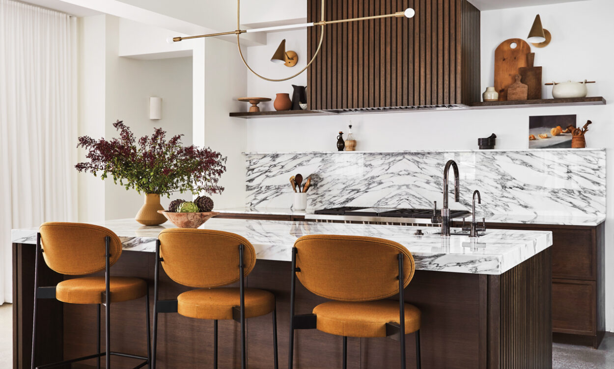 kitchen with a wood hood cover, marble counters and backsplash, leather pendant, and counter stools