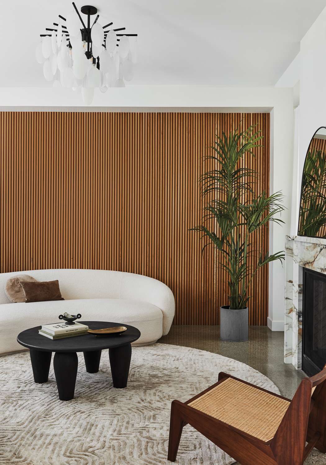 wellness room with accent wall of slatted oak and white curved sofa beside round wood coffee table