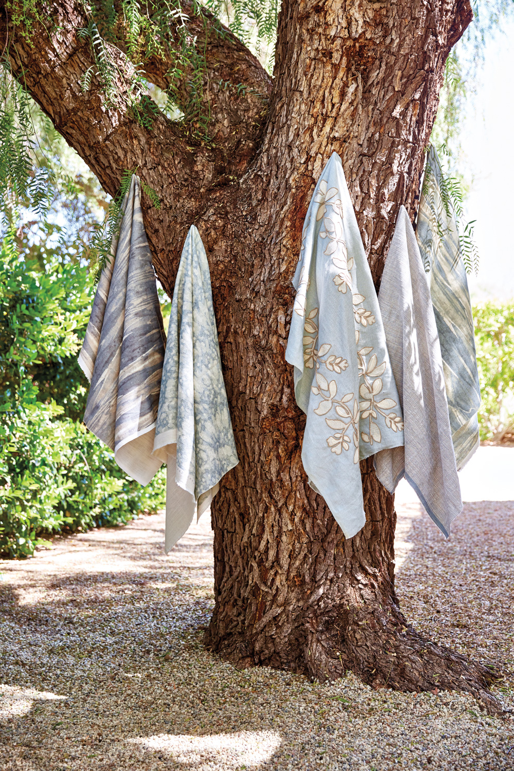 Barbara Barry x Kravet Ojai textiles in shades of blue hanging from a tree outdoors