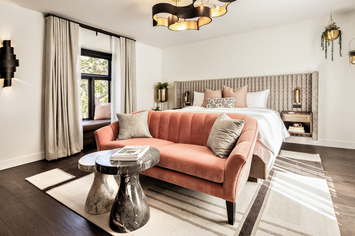 Bedroom at Orli La Jolla with a peach-colored tufted loveseat and a pair of marble coffee tables 
