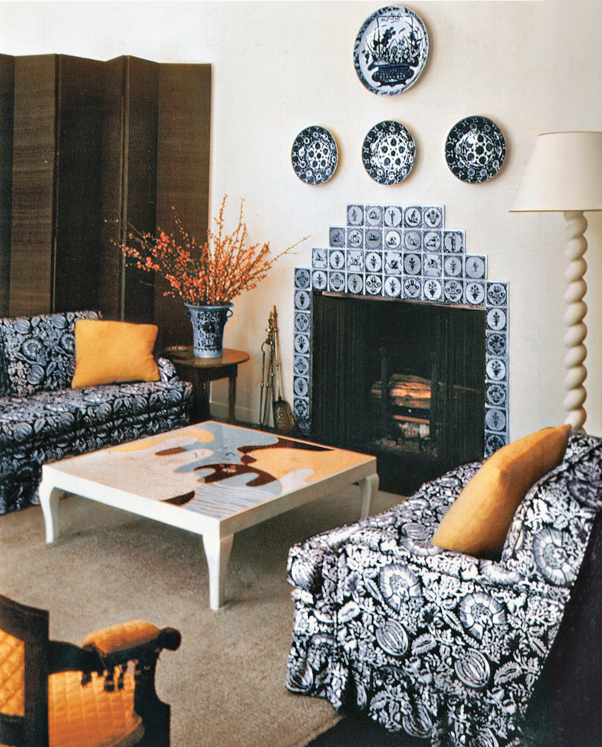 Living room decorated by Frances Elkins with patterned armchairs around a coffee table with an abstract-art motif, facing a patterned fireplace