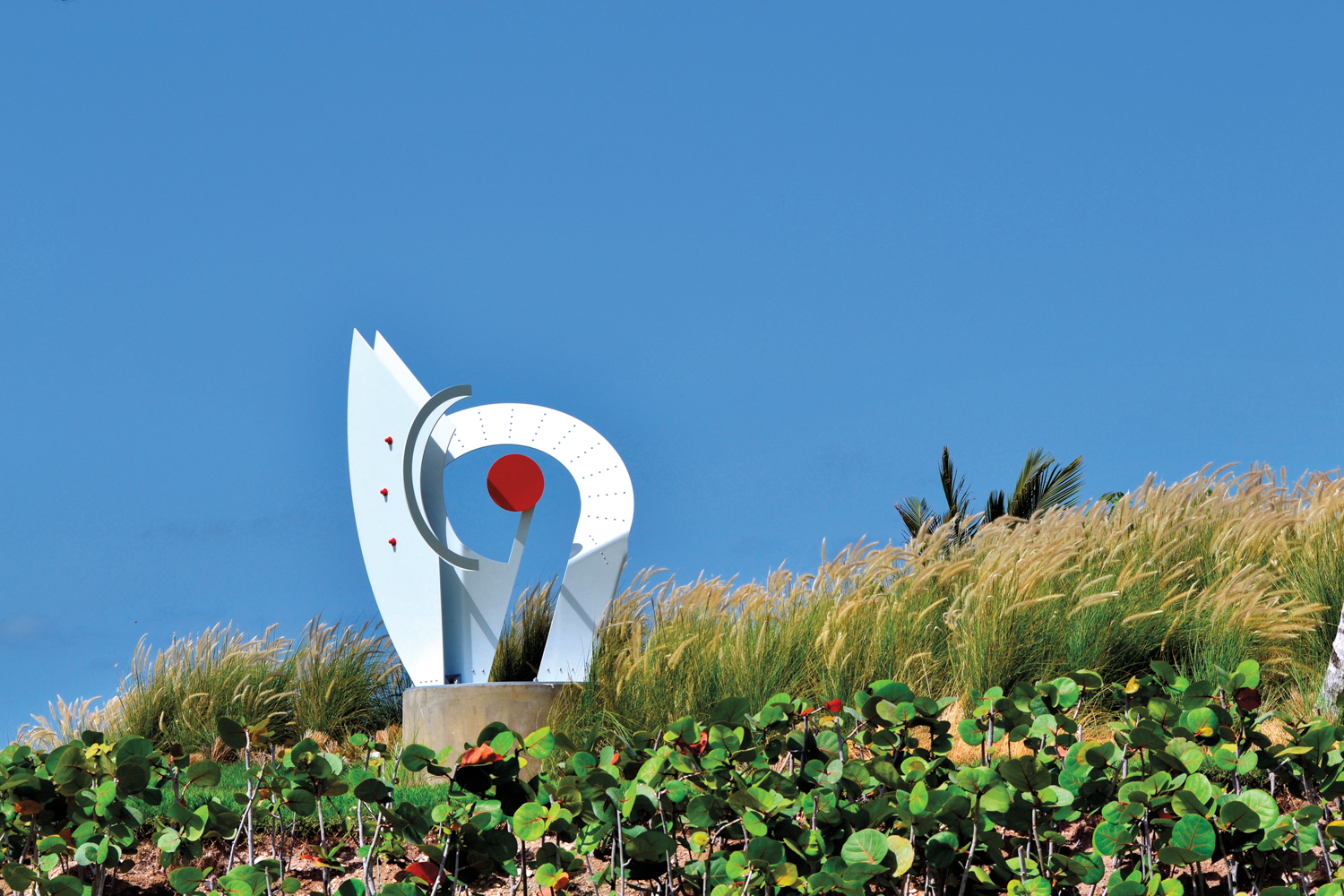 large white aluminum sculpture with red details in the Caribbean by Jorge Blanco