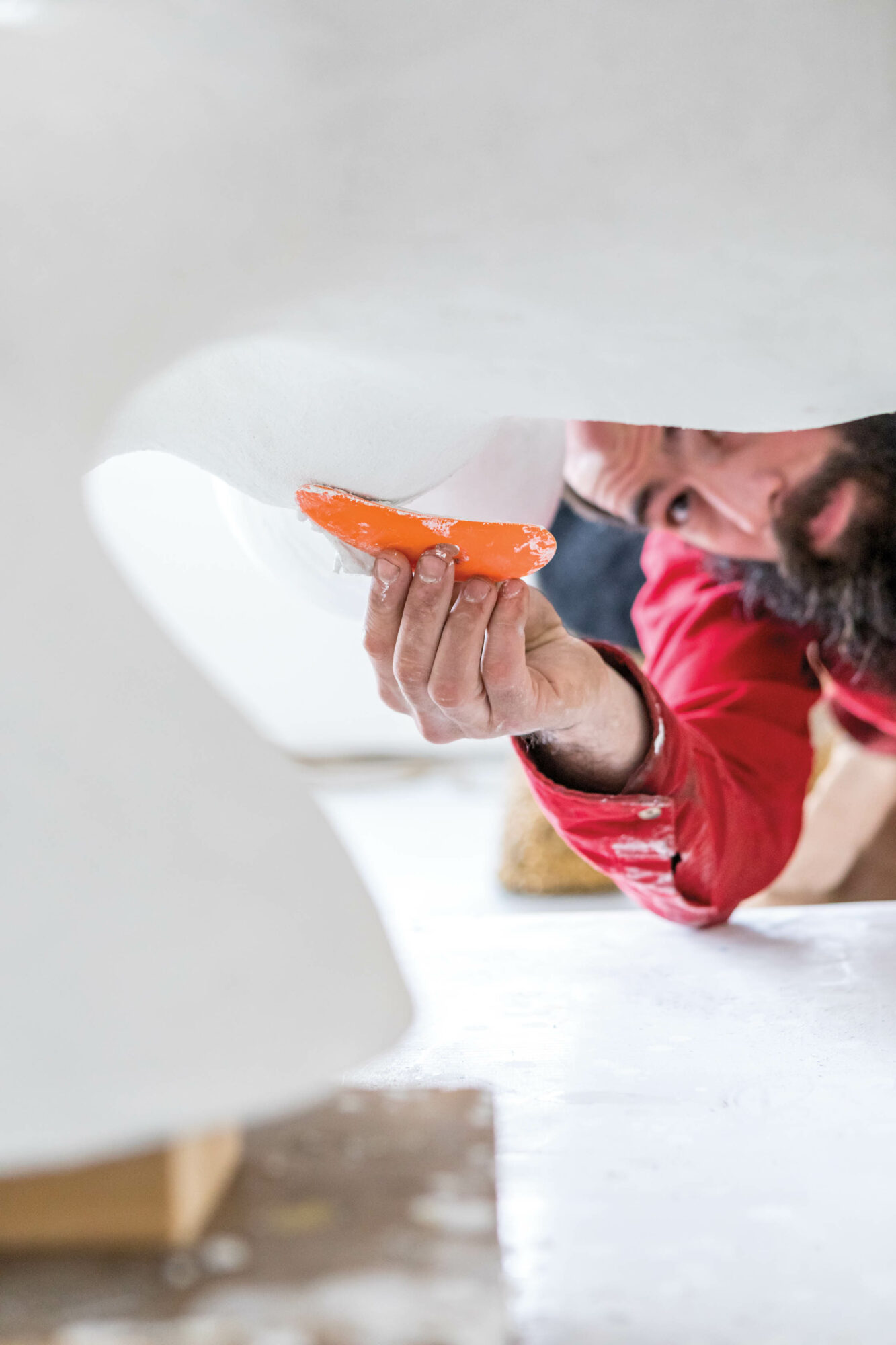 Artist J McDonald using an orange scraper on his white sculpture