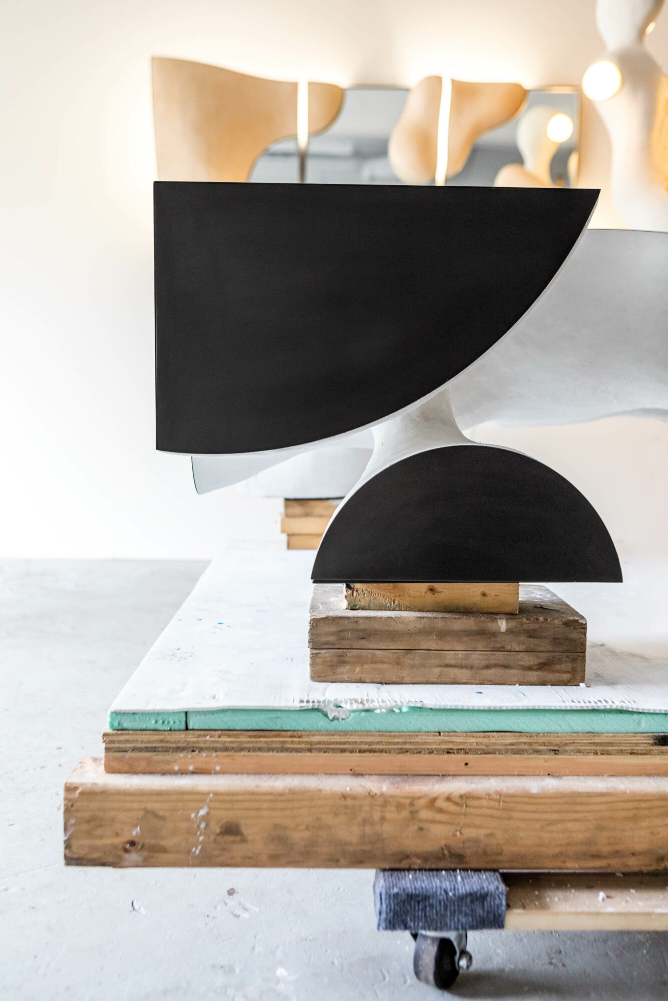 black ovular sculptures on white wooden planks by J McDonald