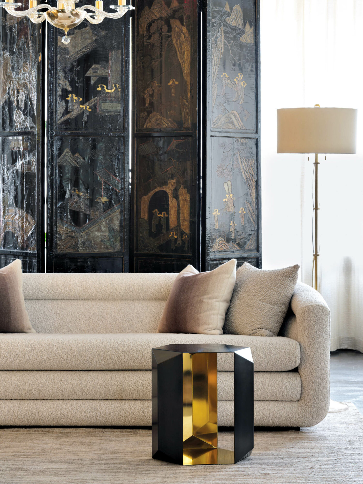 A white sofa on view at a Donghia showroom next to a room divider and a black-and-gold side table