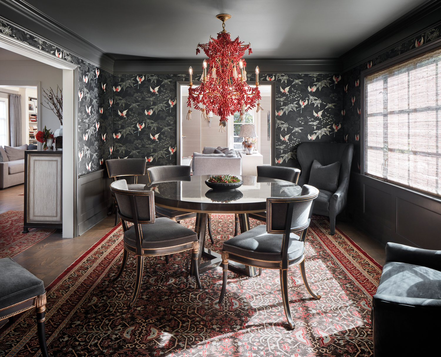 Dining room with a red chandelier, patterned metallic and black wallpaper and black dining set