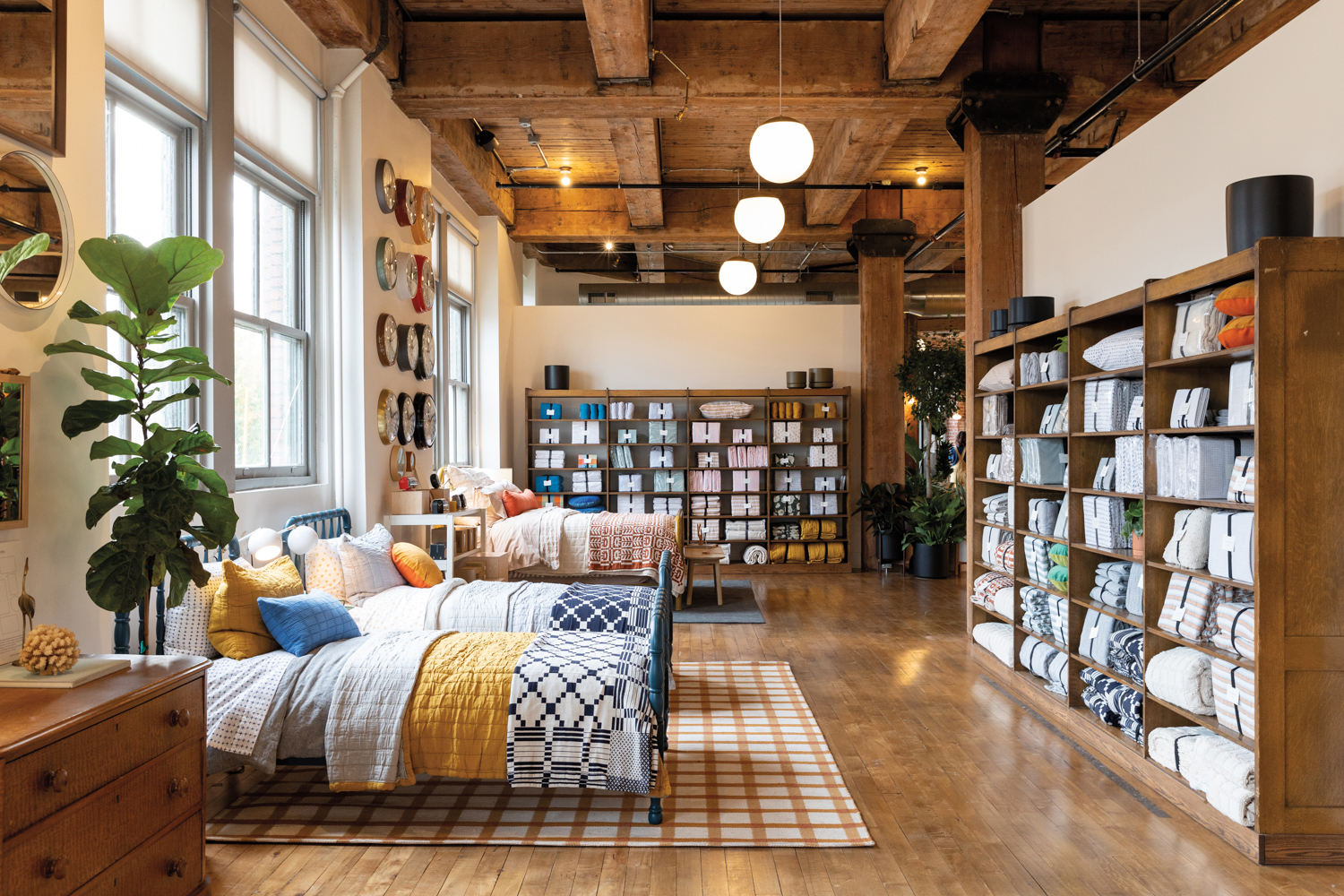 warm showroom by Schoolhouse with beds, linens, and wood