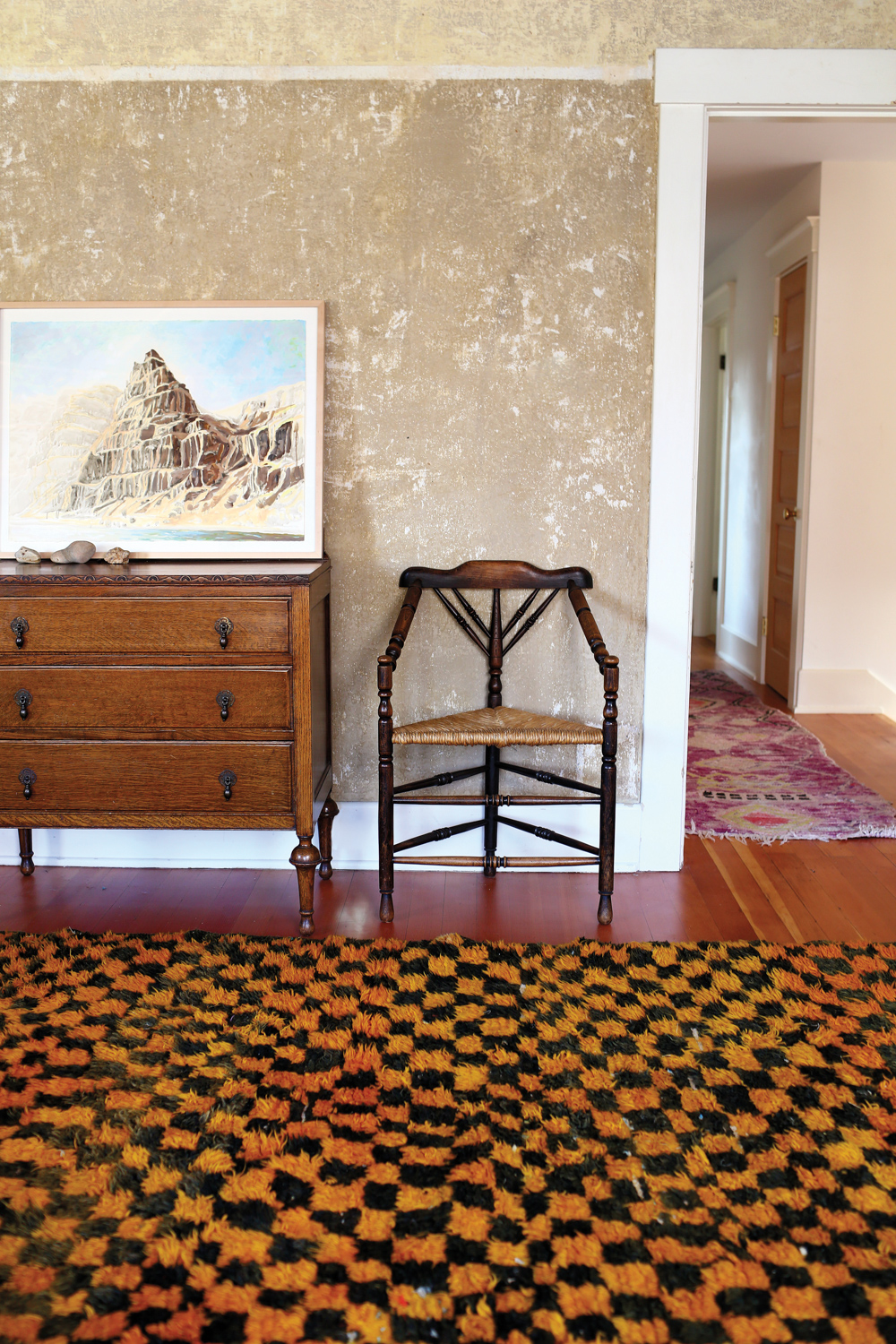 orange and black moroccan rug from Kat + Maouche with wooden chair and chest of drawers