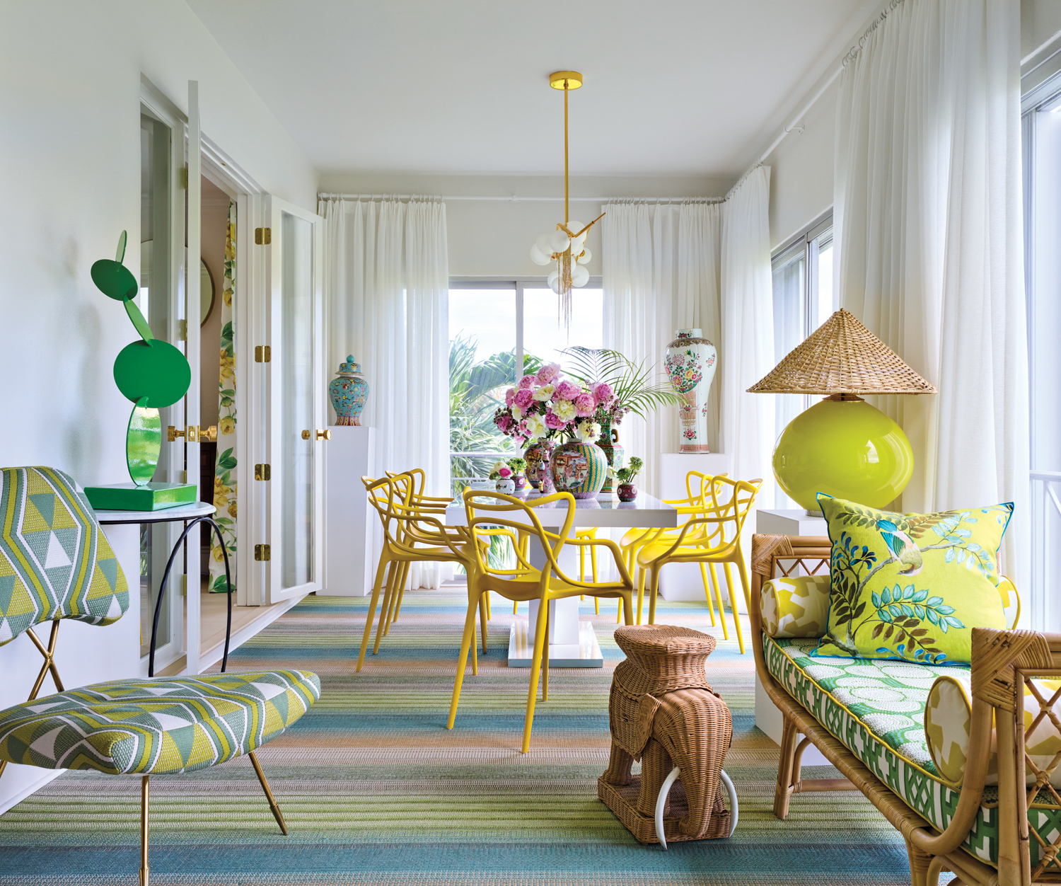 dining room with yellow chairs, elephant side table and sculptural chandelier