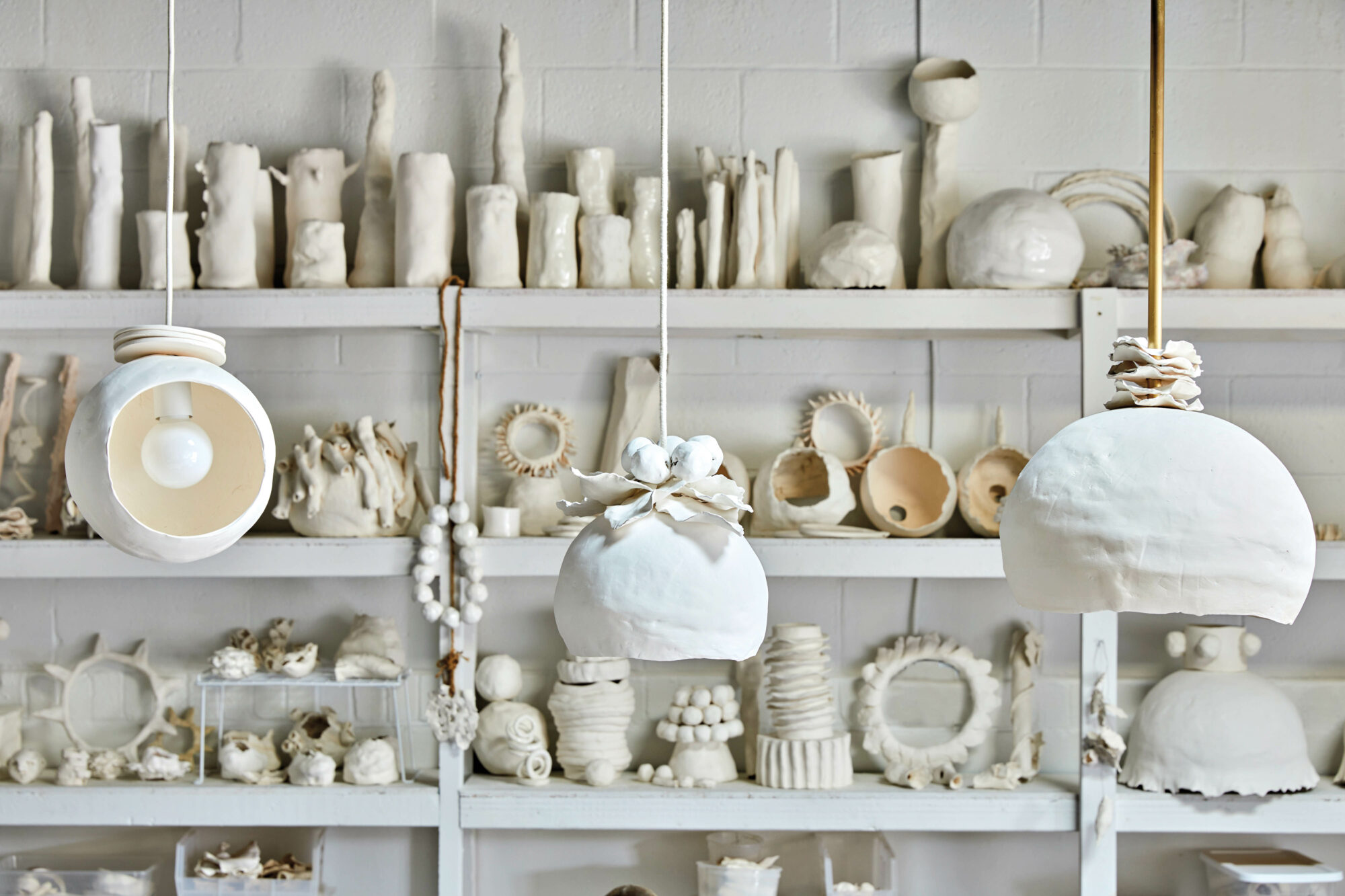 White studio with open shelves supporting ceramic objects created by Dana Castle