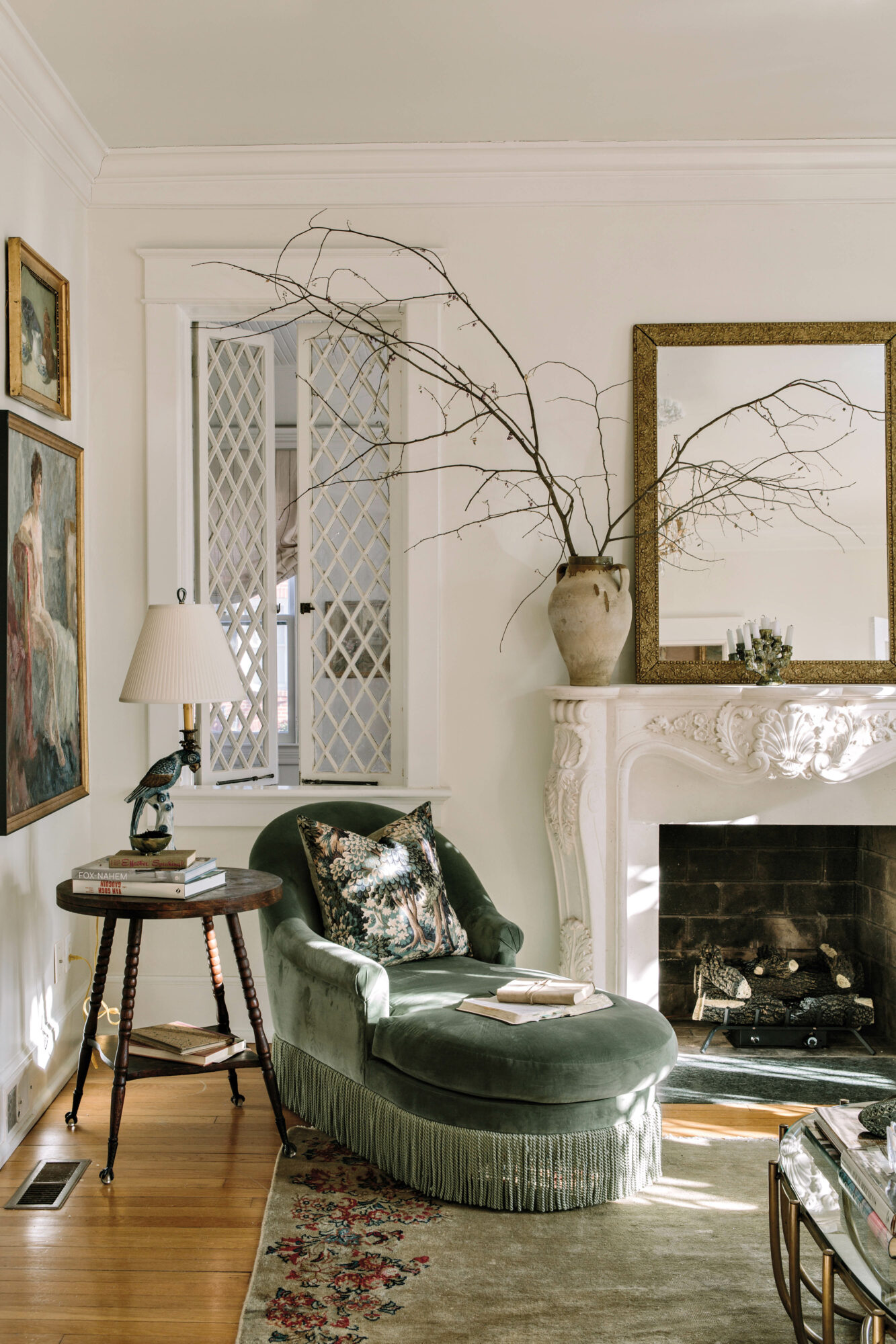 Living room corner with green-velvet chaise underneath an interior window with white latticework