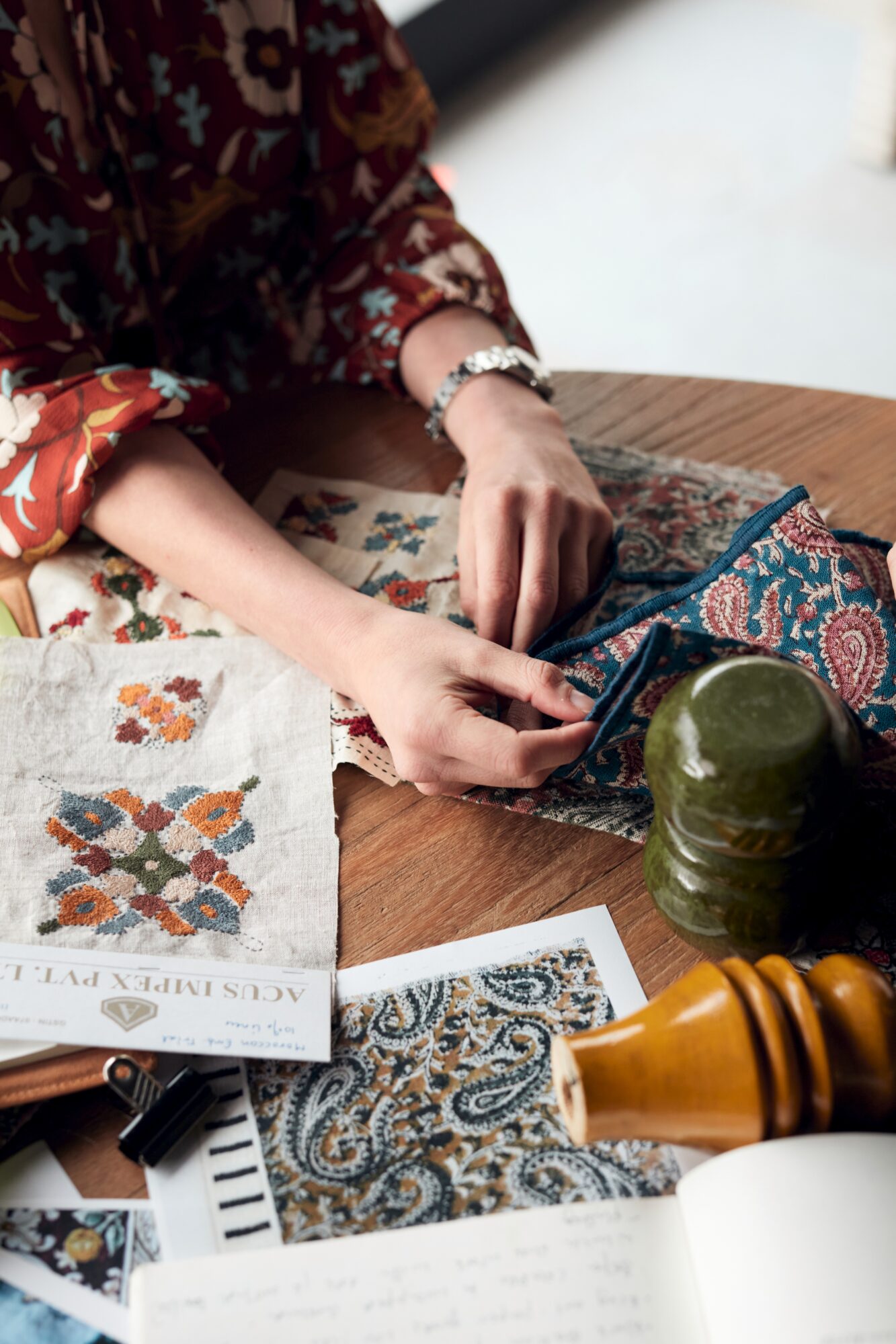 Woman's hands on a table holding fabric and wood samples