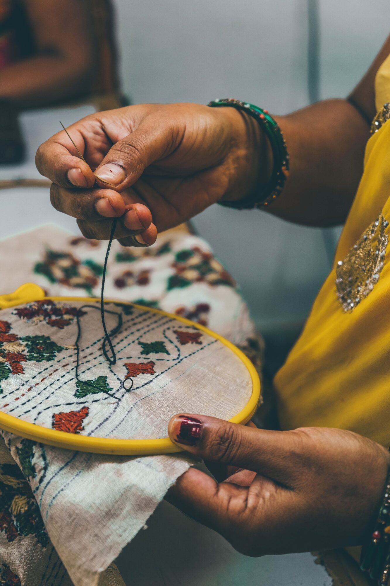 A woman's hands holding a needle and thread for hand embroidery
