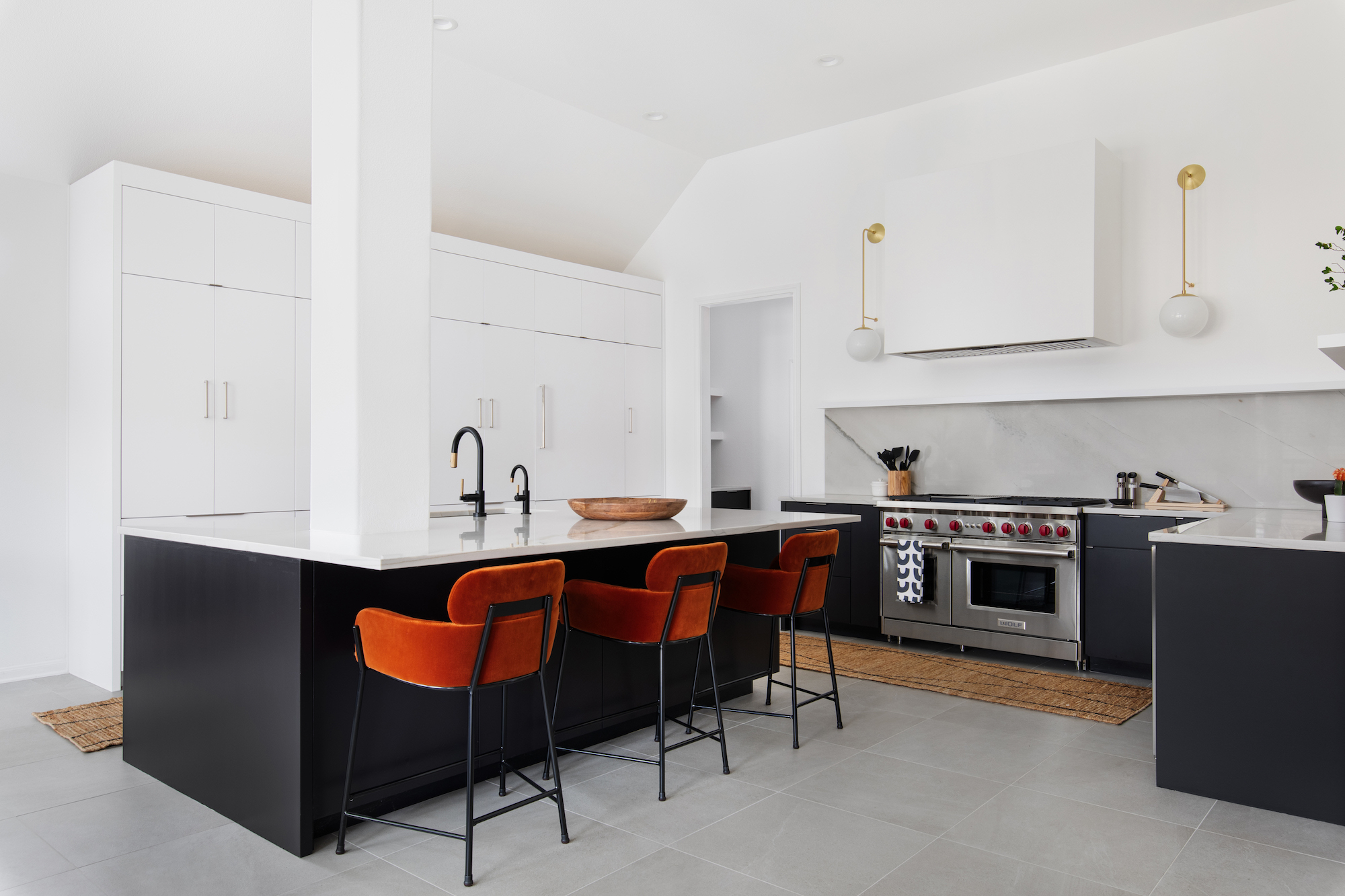 white contemporary kitchen with black island and tan bar chairs