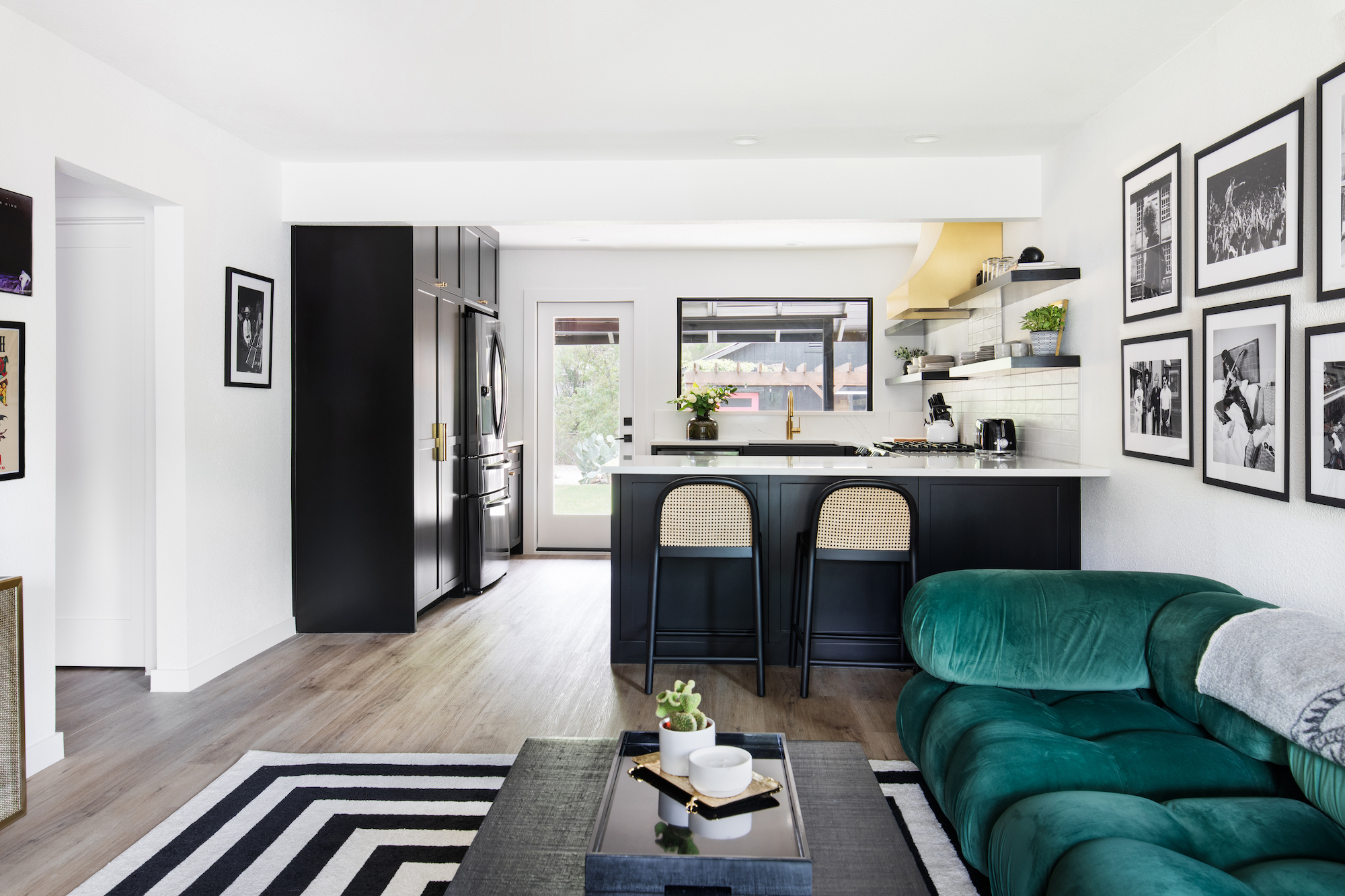 great room with teal sofa and dark cabinets in kitchen