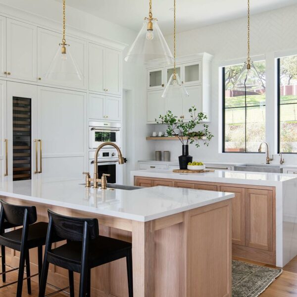 White countertops on wood islands in light and airy kitchen
