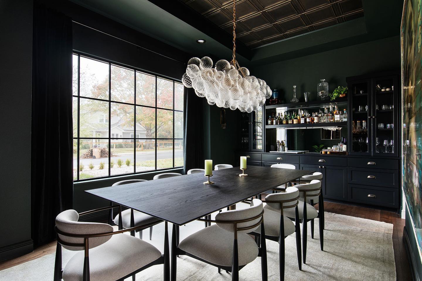 Dark green paint in dining area with modern table and bubble light