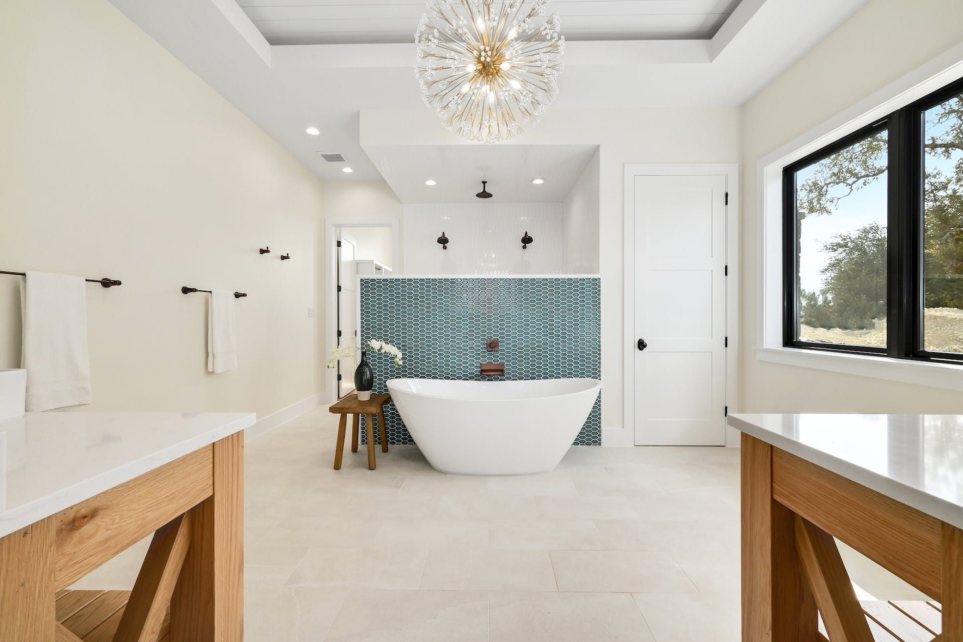 White soaking tub against blue tile and chandelier