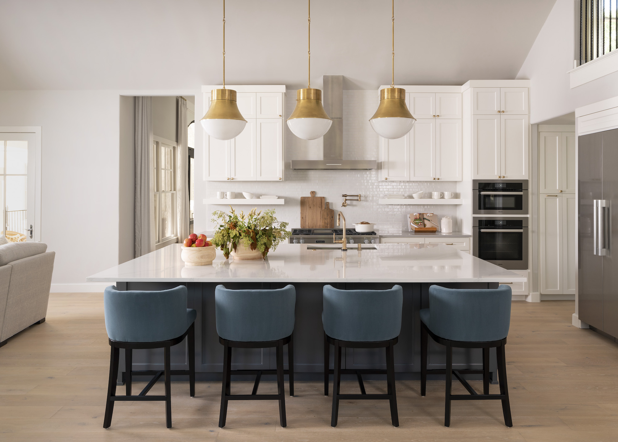 white kitchen with teal bar stools an pendant lights