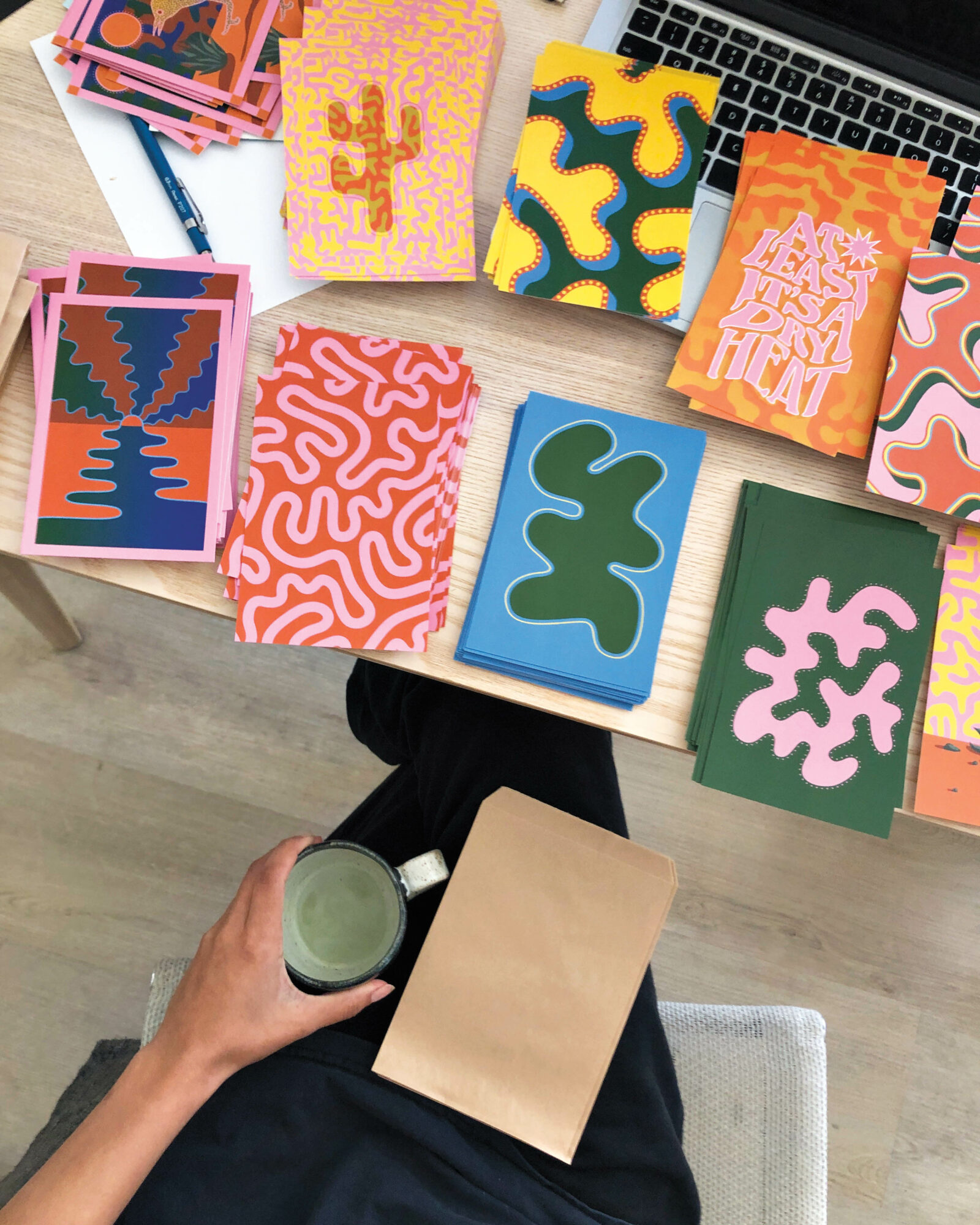 Stacks of colorful abstract art prints on a wood table