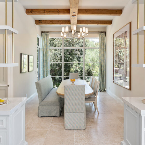 White kitchen in Southern California home leading into a contemporary dining room with wood beams.