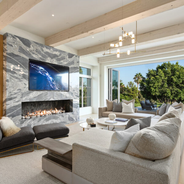 Living room in Southern California home with marble fireplace, gray sectional and built in cabinets.