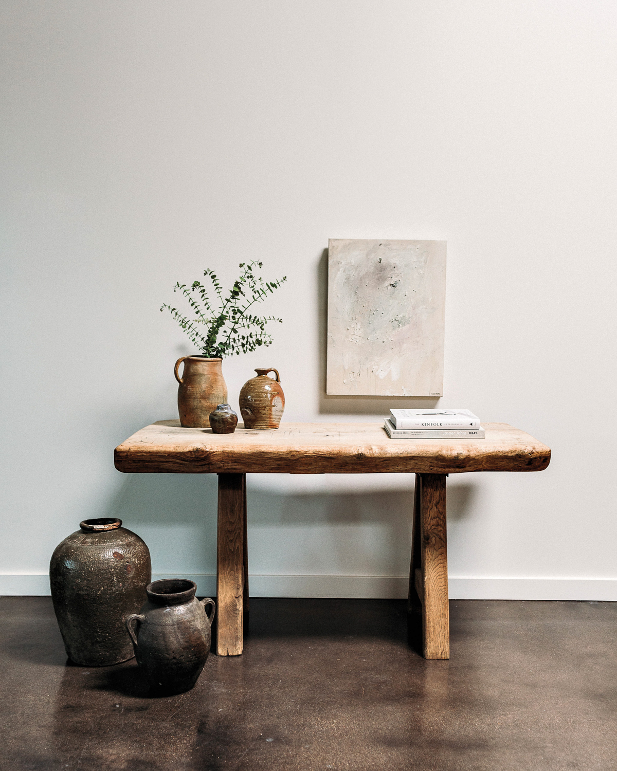 Artwork hangs above a wood console table styled with pottery and white books at The Selby House