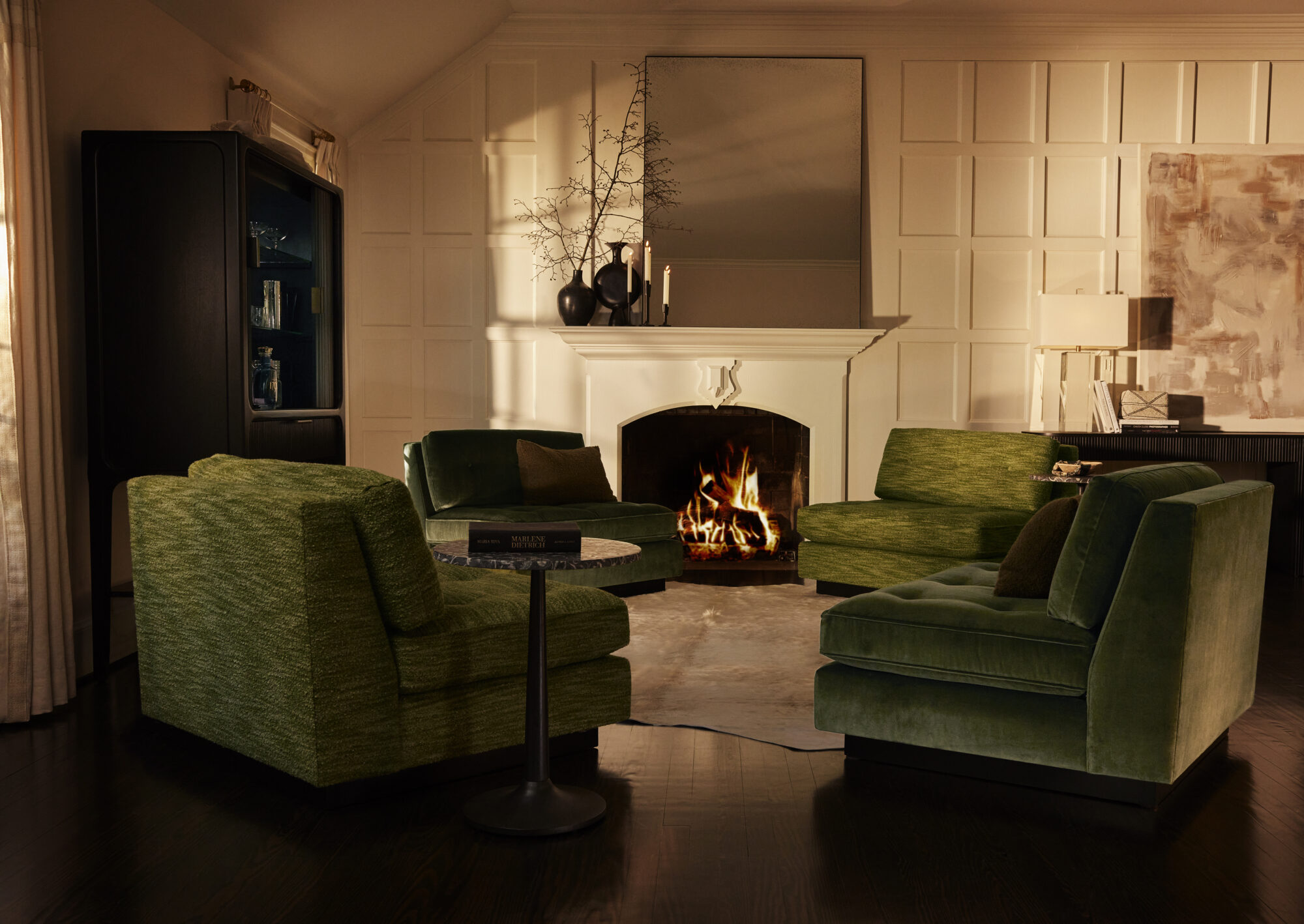 dark room with velvet green armchairs, fireplace and mirror