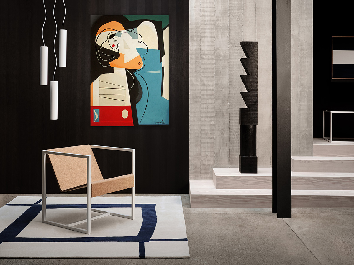black gallery wall with abstract art of woman, geometric chair, cylindrical lighting and white rug