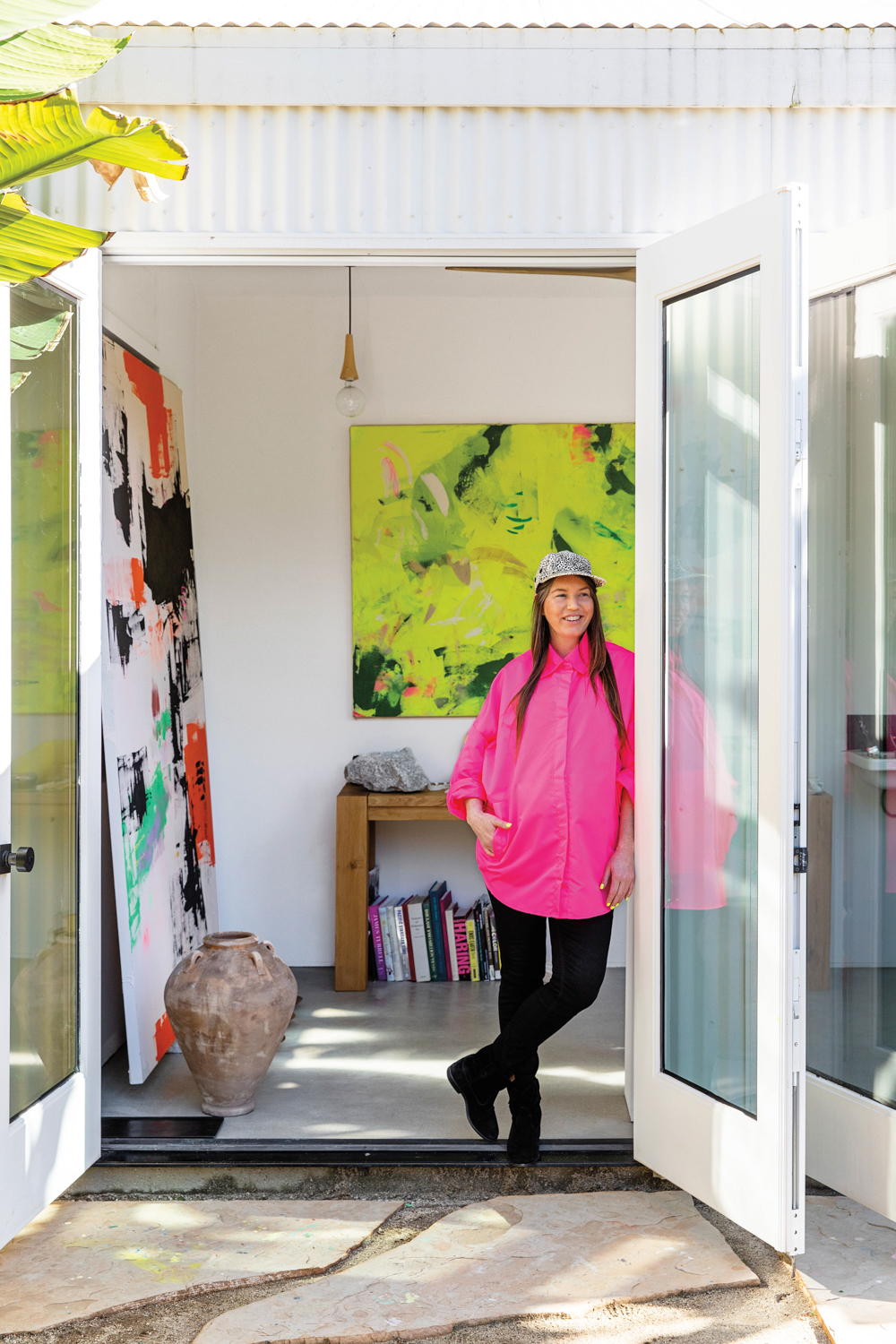 Ali Beletic wearing a pink shirt posing in doorway of art studio 