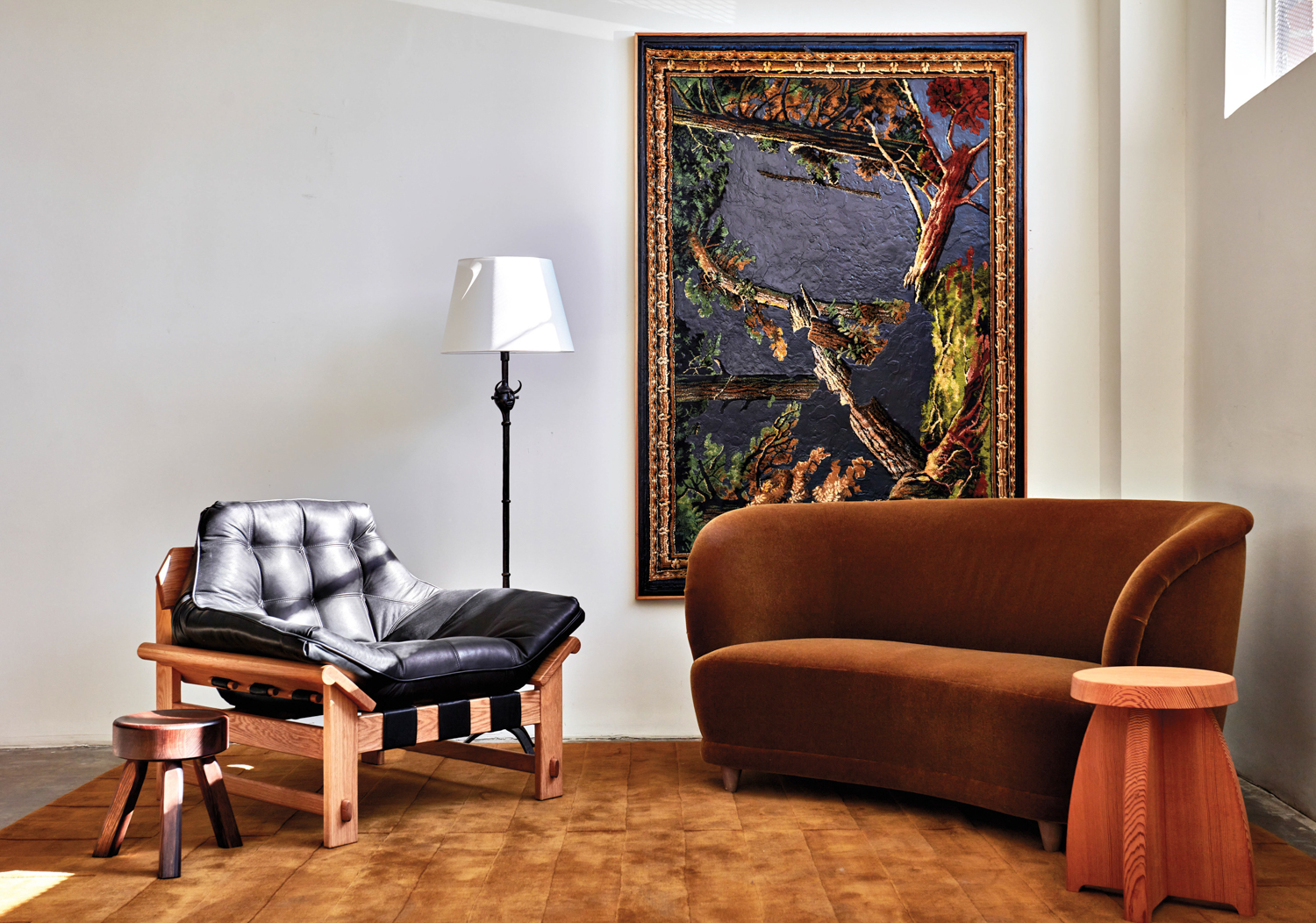 The Expert showroom with a leather-and-wood armchair facing a brown, curved sofa under a tapestry