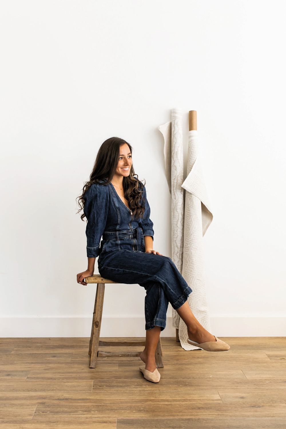 Portrait of Amy Weisberg sitting on a stool with rolls of white fabric behind her