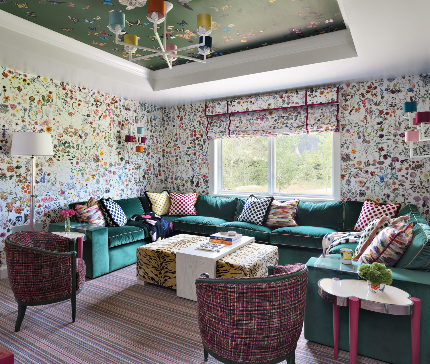 Room with floral wallpaper, teal sectional, green painted ceiling, tiger-print table and striped rug