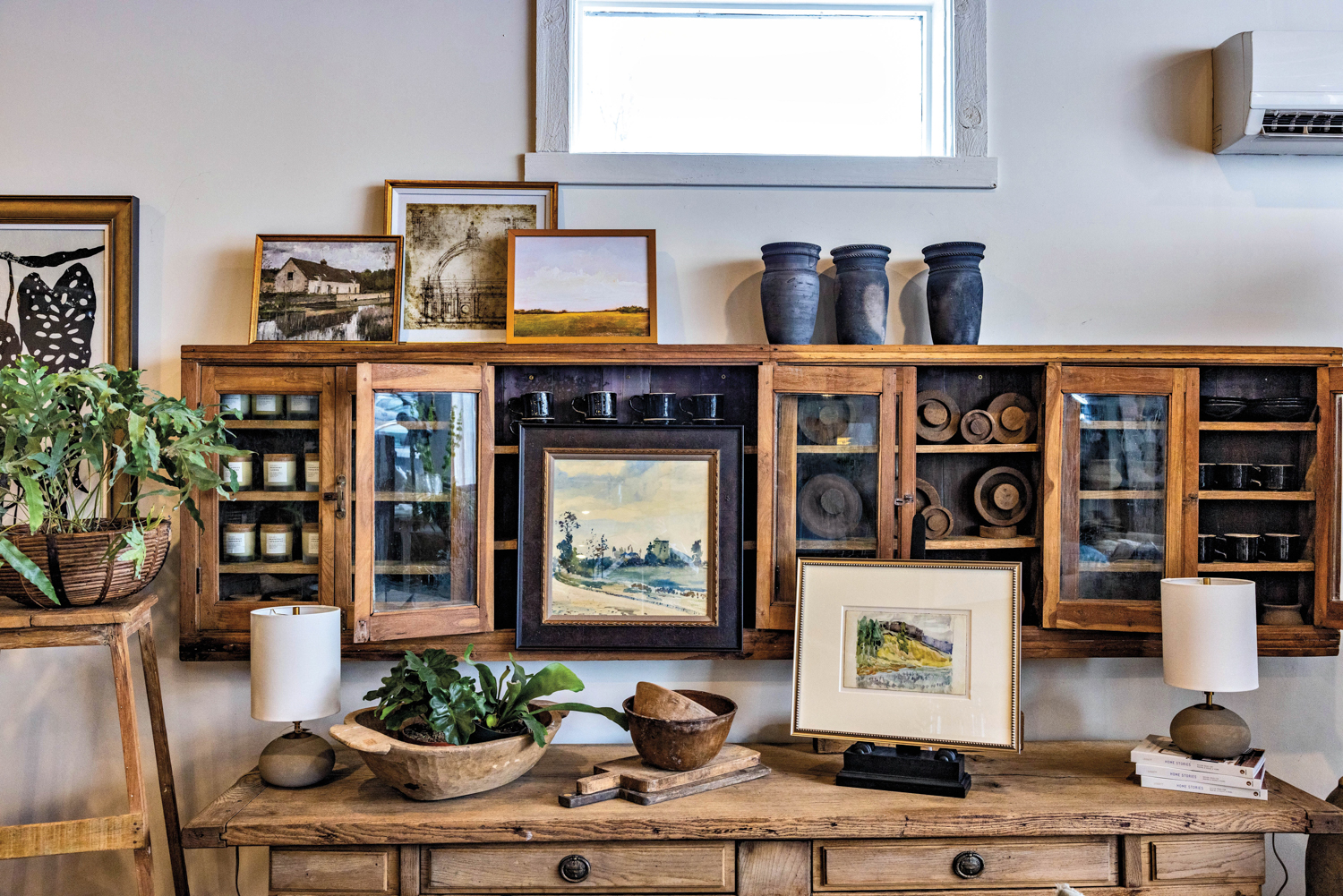 Woden display case mounted on wall with vases, mugs, artwork and other antiques on display