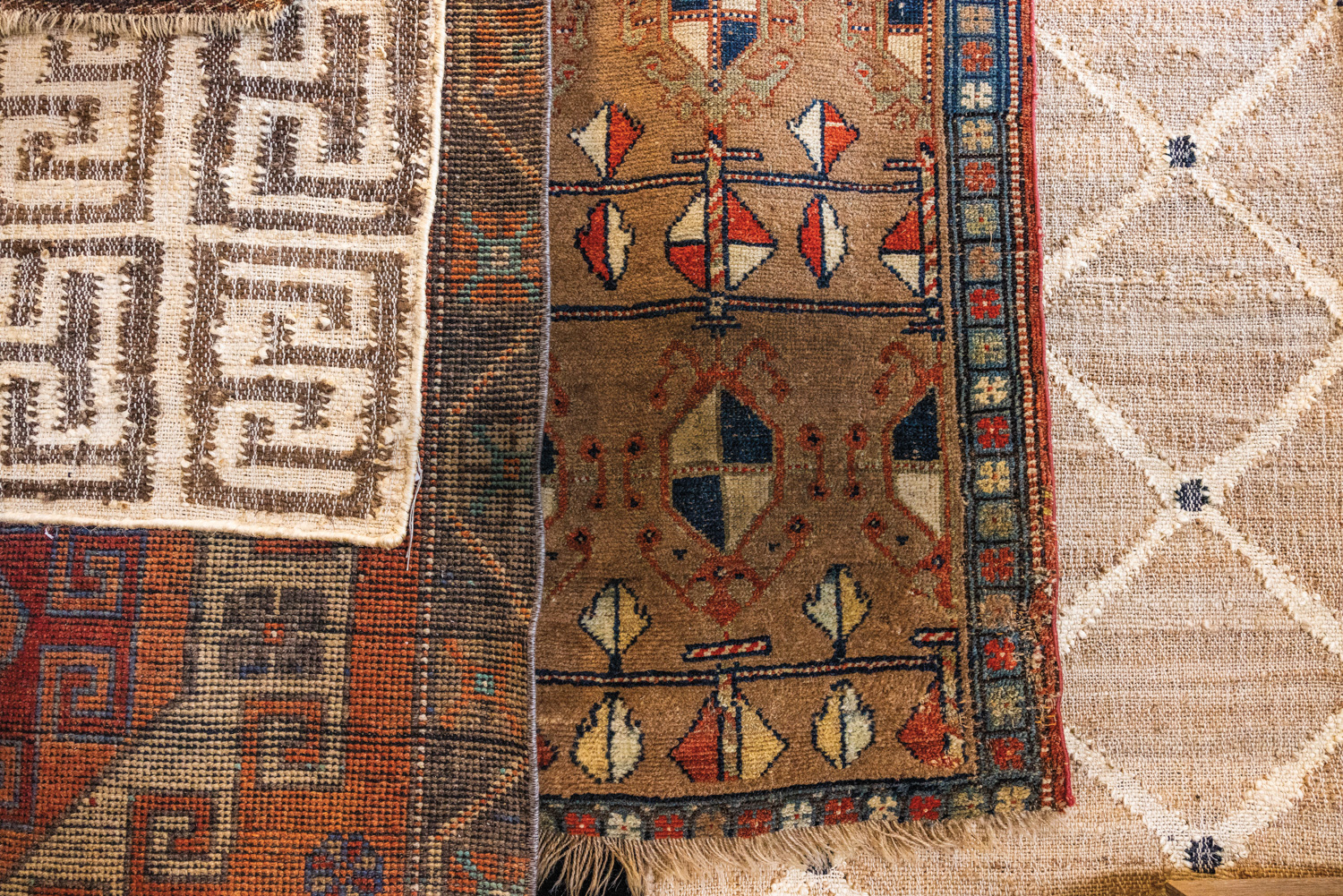 close top angle of layered colorful antique rugs