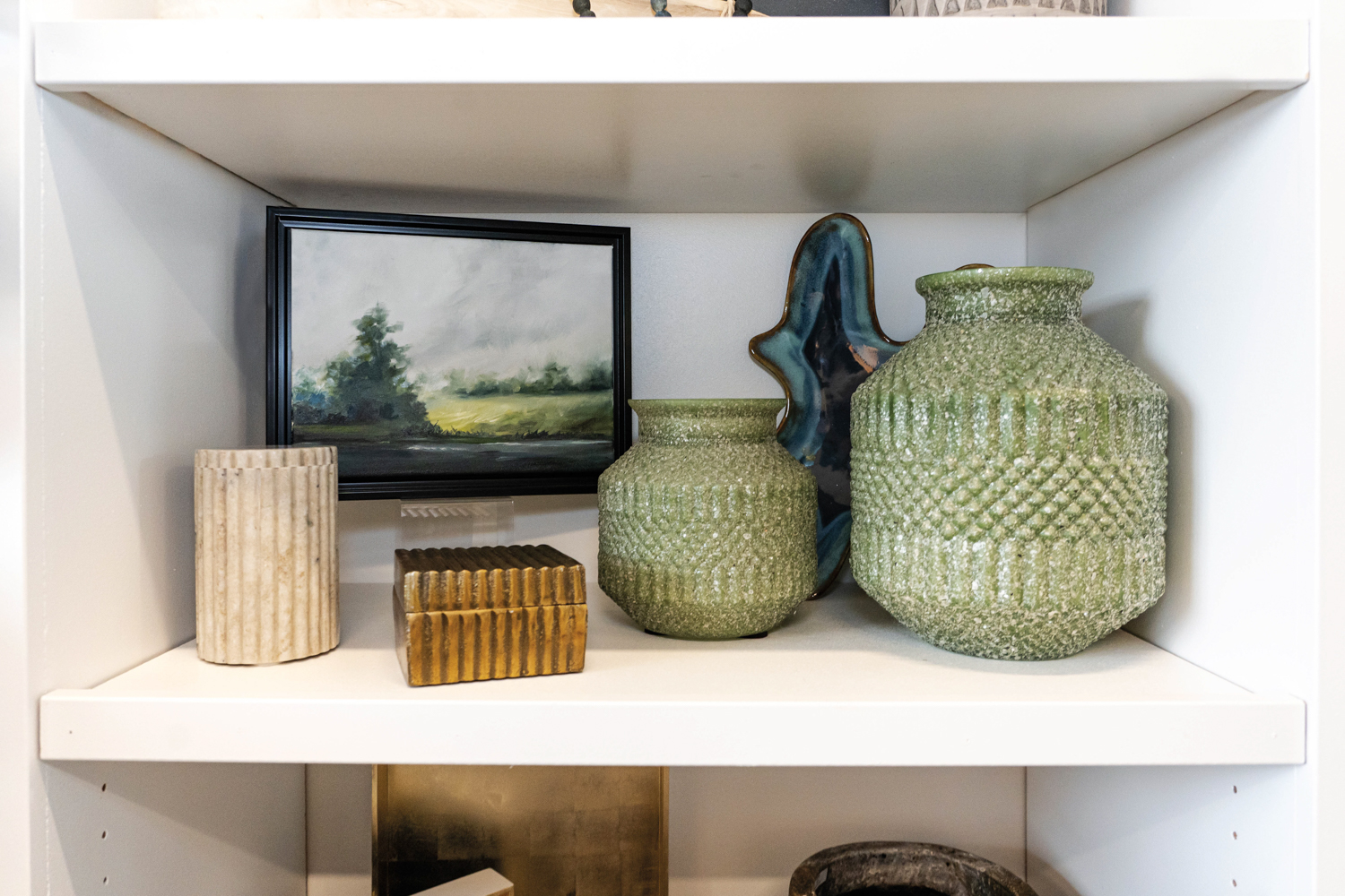 A small landscape painting and different ceramic vases on a display shelf in Julie Kay Design shop