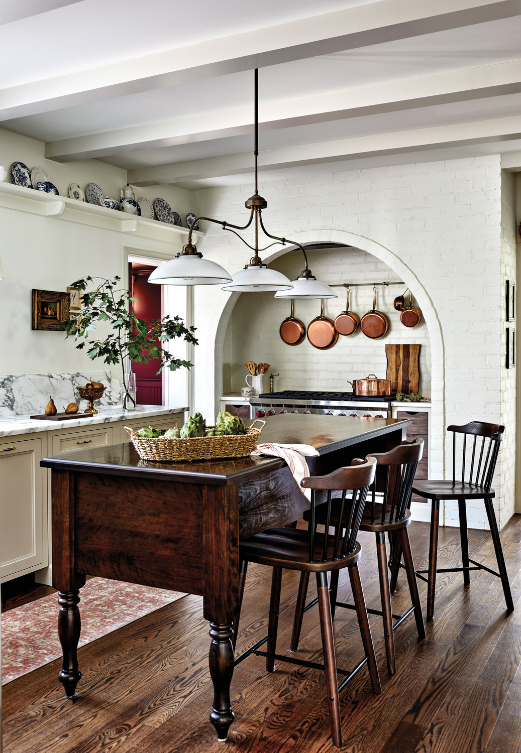white farmhouse kitchen with mahogany dining table and hanging pendants
