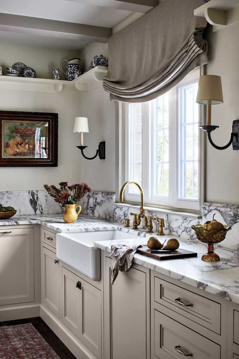 closeup of sink with marble countertops, gold faucet and sconces by Winsome Interior Design