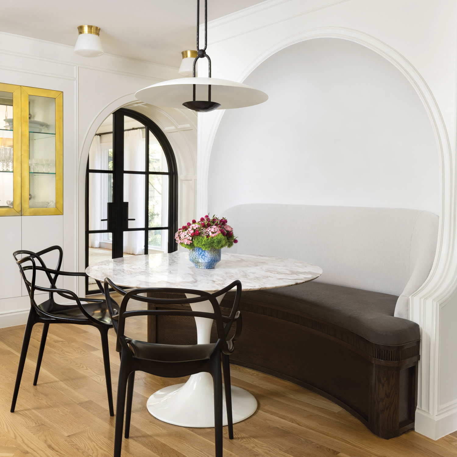 white breakfast nook with brown banquette, marble table and black chairs by Maestri Studio