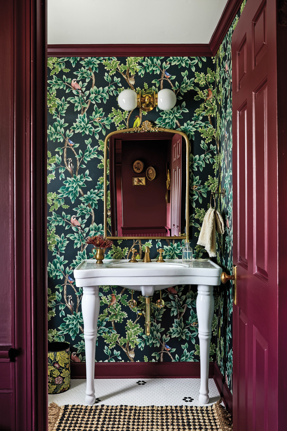 powder room with botanical wallpaper, white sink, gold mirror and red doors by Winsome Interior Design