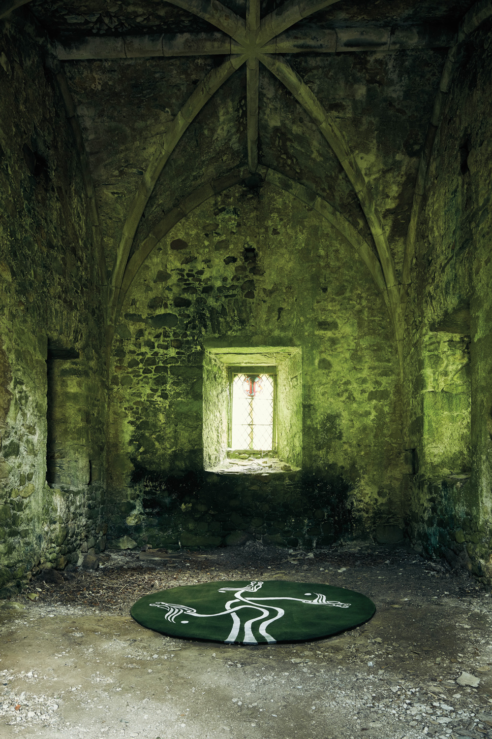 circular green rug inside dark arched building