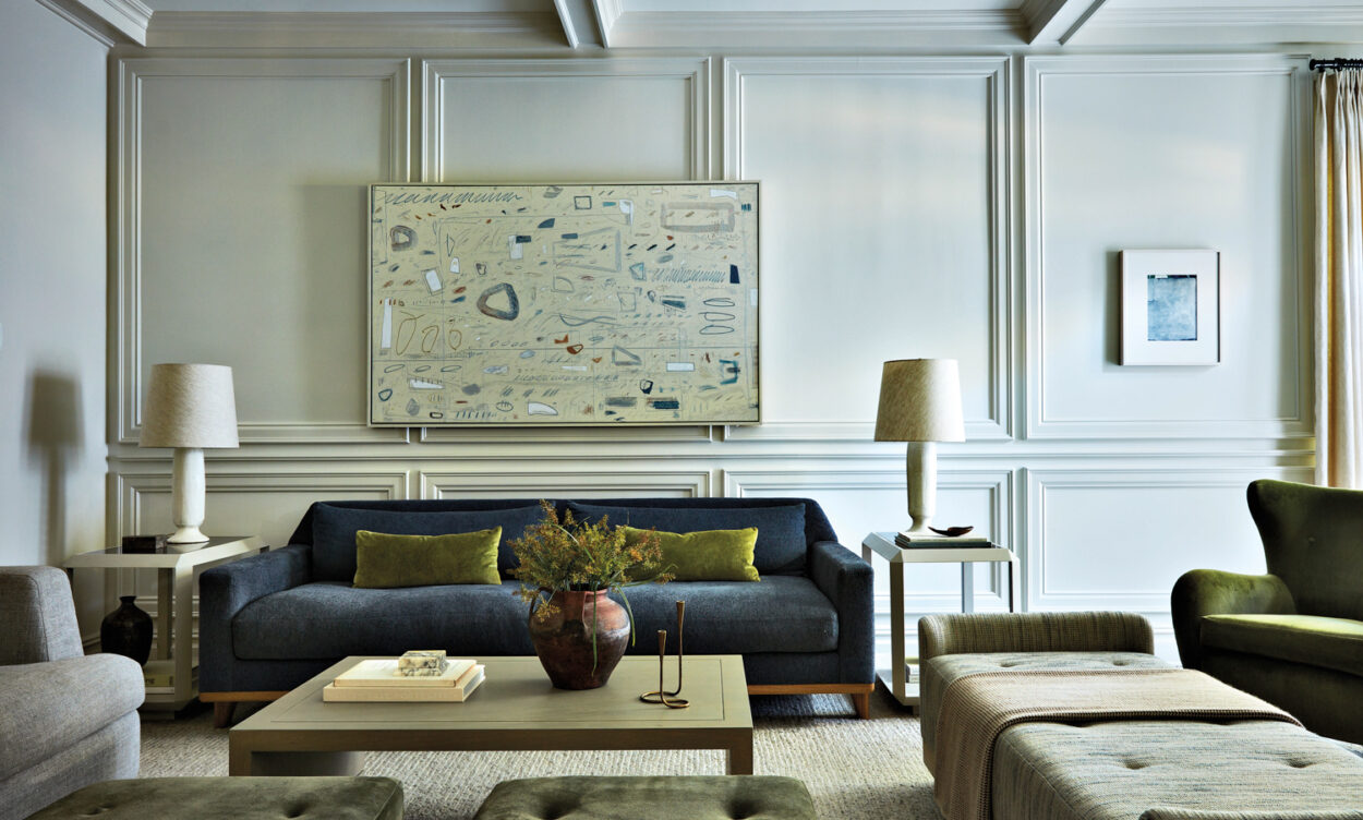 living room with warm white paneling, blue sofa and other furnishings by Joan Enger