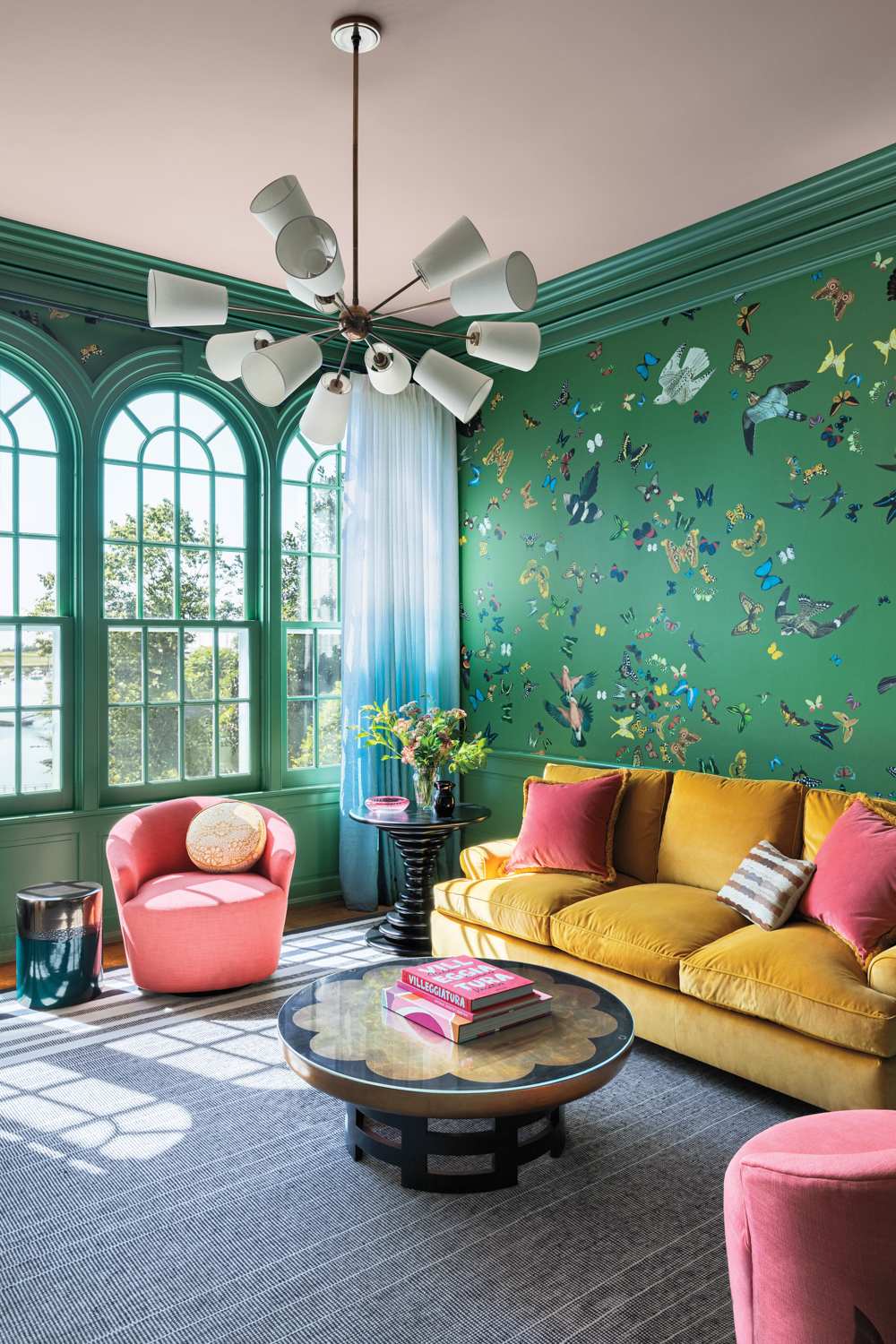 morning room with green wallpaper, yellow couch, midcentury coffee table and pink swivel chair