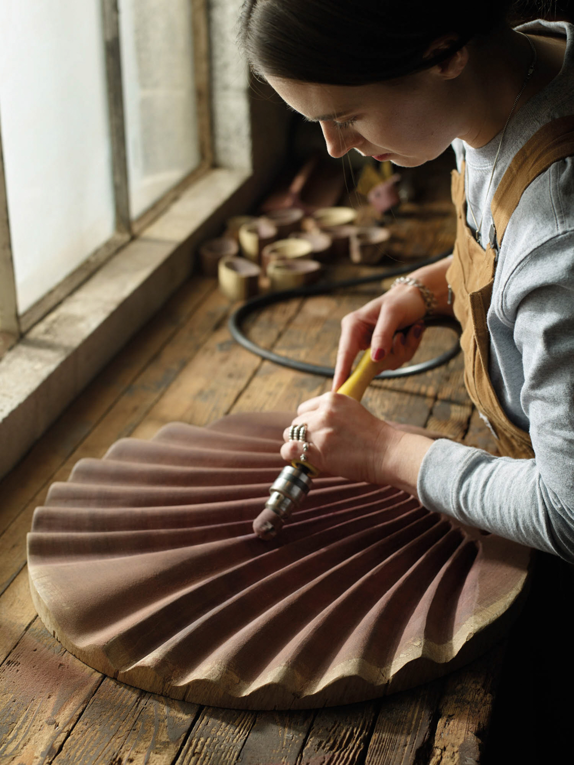 Alexandra Climent in her studio sculpting a shell-shaped music stand from tropical wood