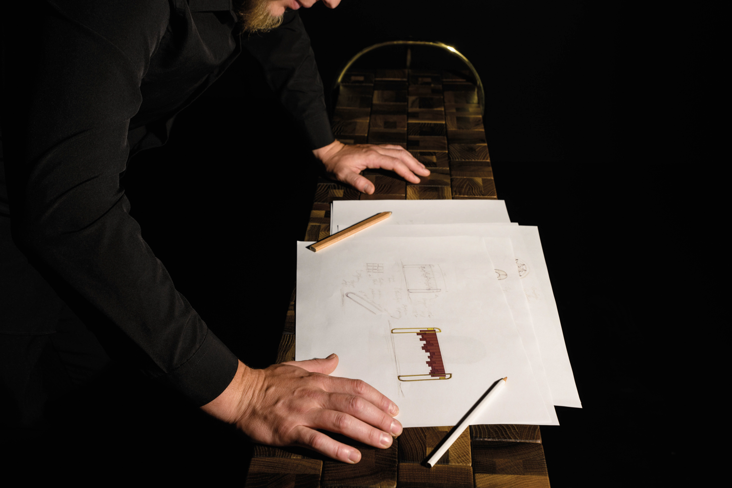 a man looking over some design sketches for the collection