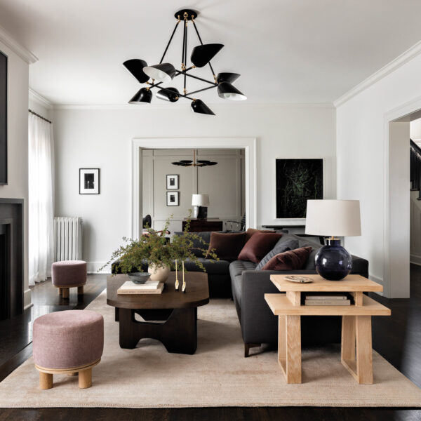 A sectional, coffee table and chandelier is centered in front of the fireplace in a Seattle Craftsman