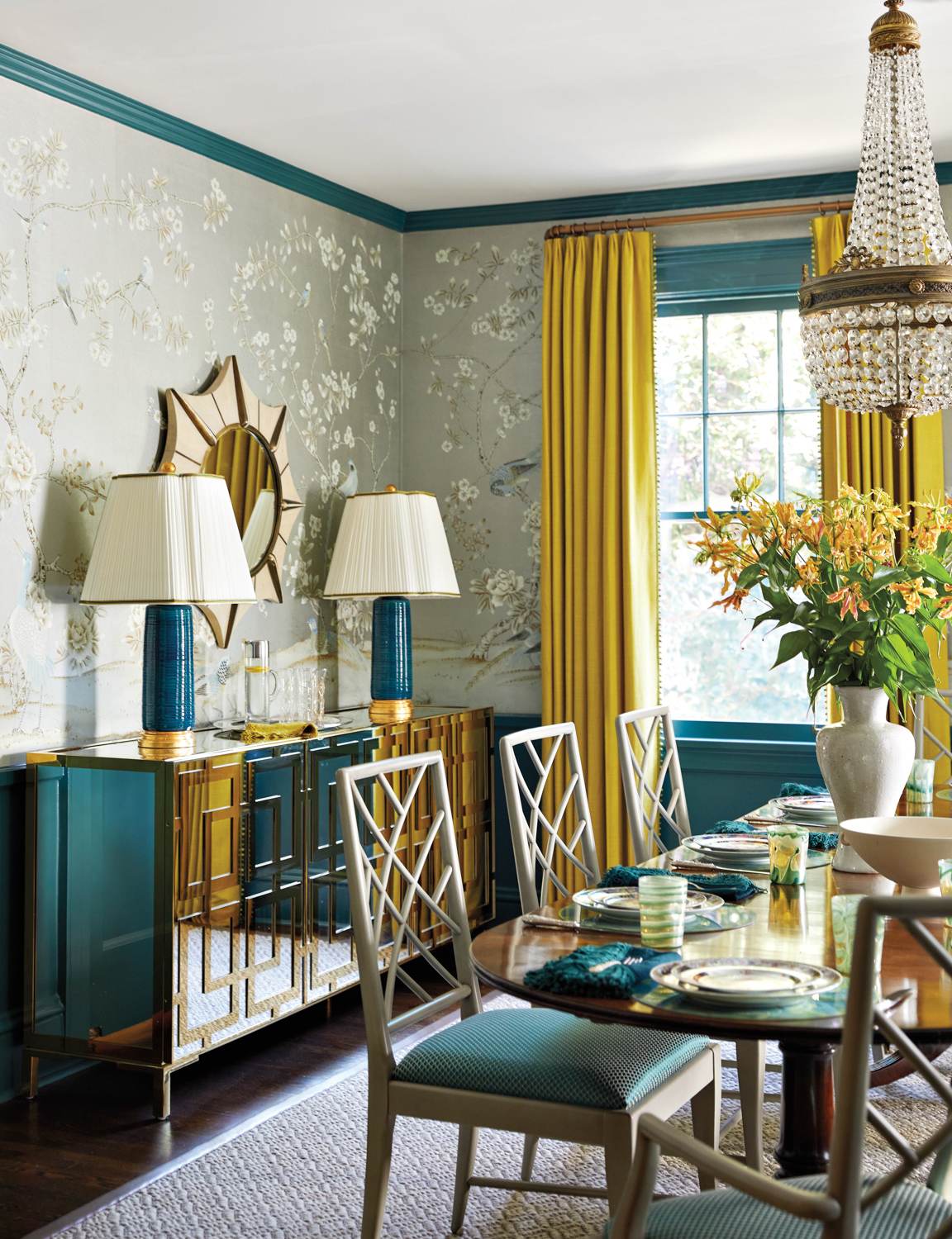 Dining room with silver metallic wallpaper, a buffet cabinet, teal millwork and matching teal lamps