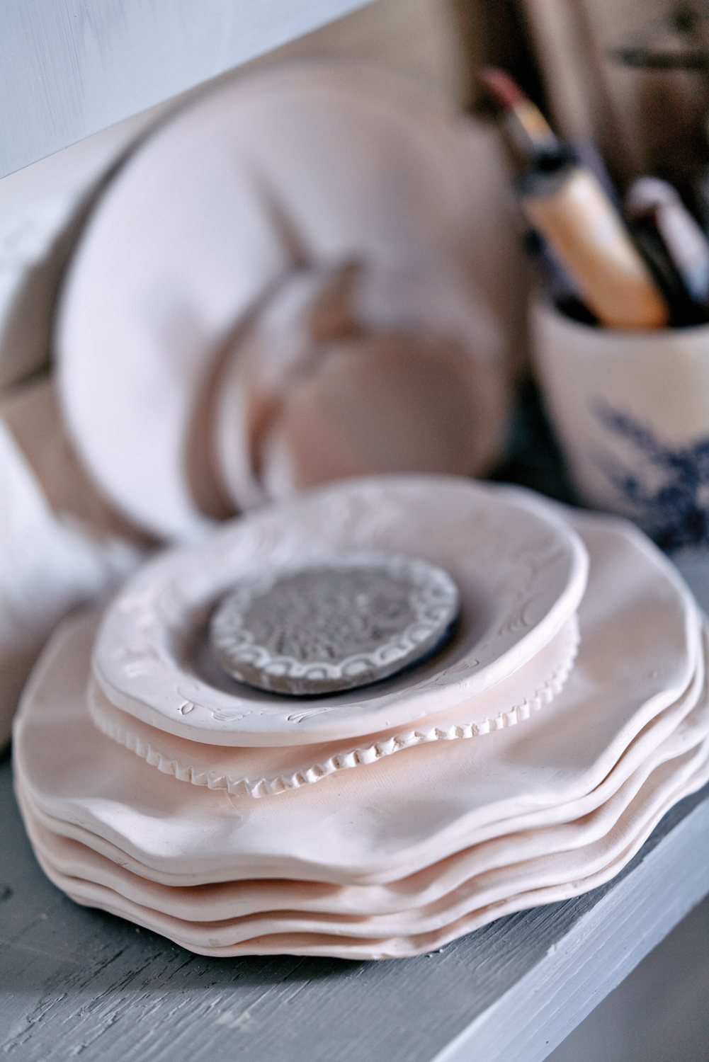 A stack of unfired ceramic plates with ruffles and small details along the edges by Maryfrances Carter